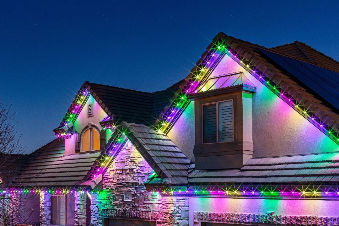 A picture of a close-up home that has 3 peaks and has a Trimlight Easter lighting pattern.