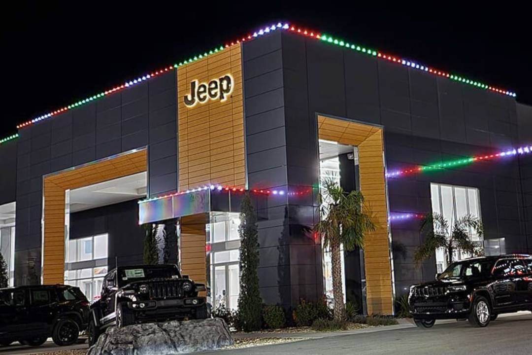 A Jeep building with cars in front and a christmas lighting pattern