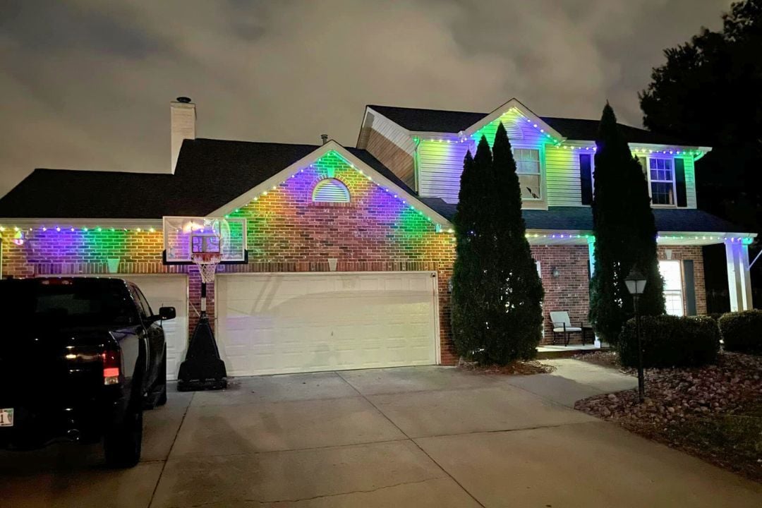 a home with trees in front and a car that has a green, yellow and purple lighting pattern.