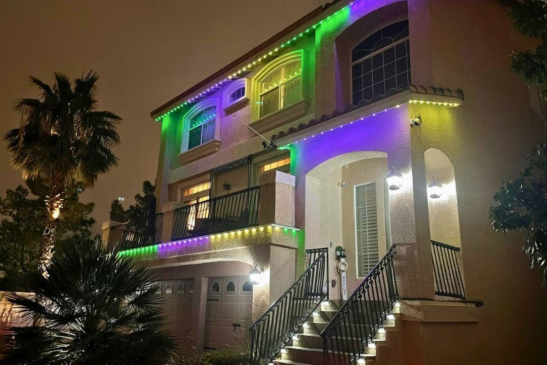 A flat roofed home with stairs that glow and has a green, yellow and purple lighting pattern.