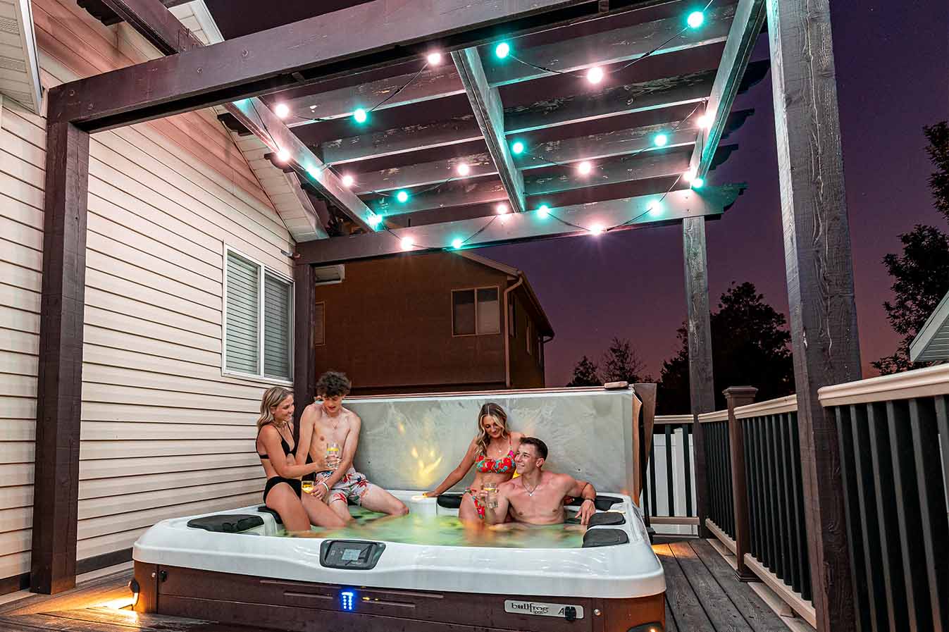 Teens hanging out in a hot tub under globe lights