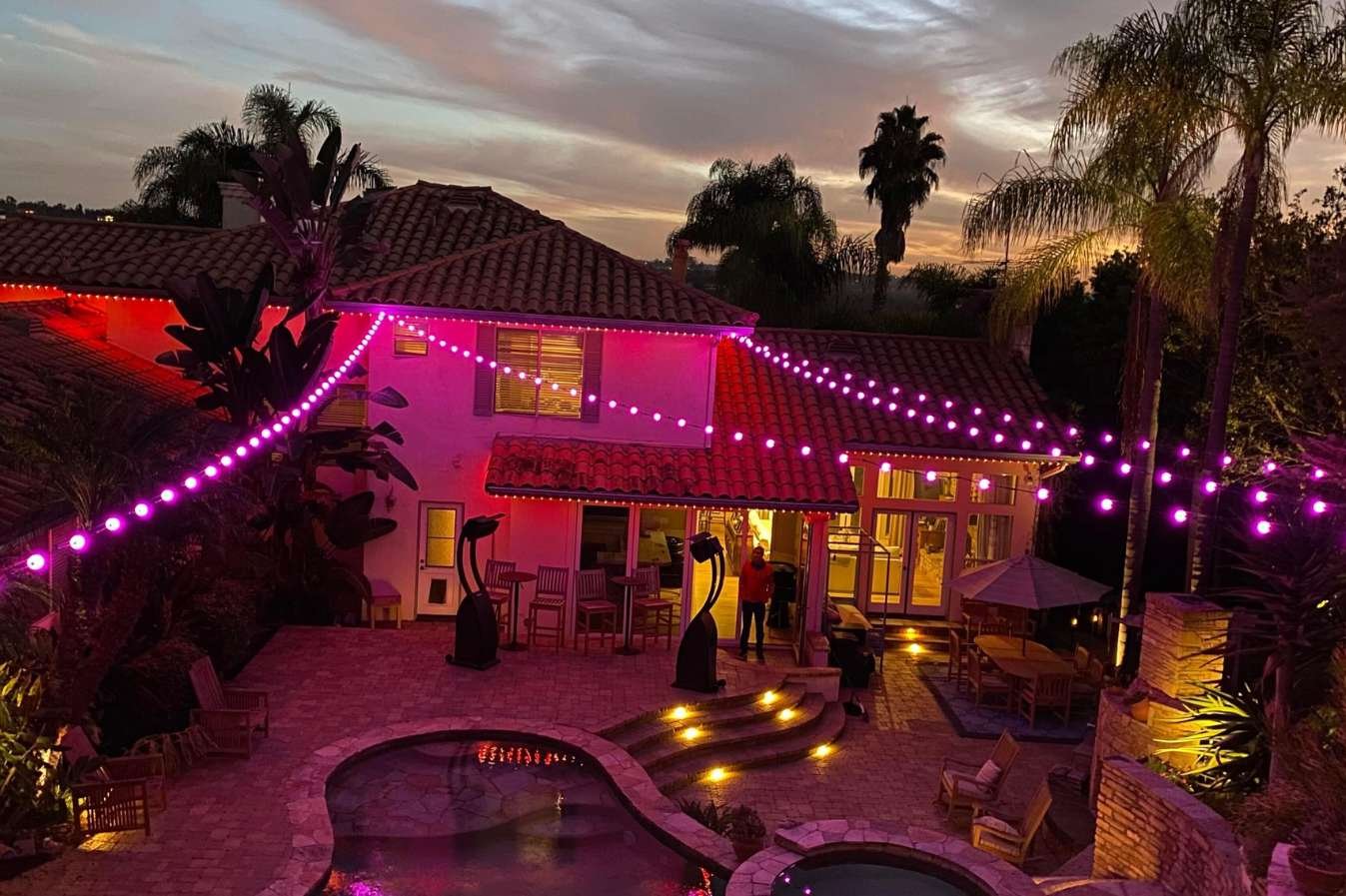 pink string lights on home with pool in backyard