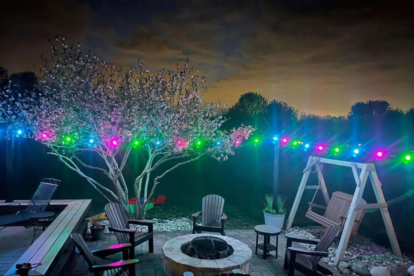 color changing bistro lights around fire pit and Adirondack chairs