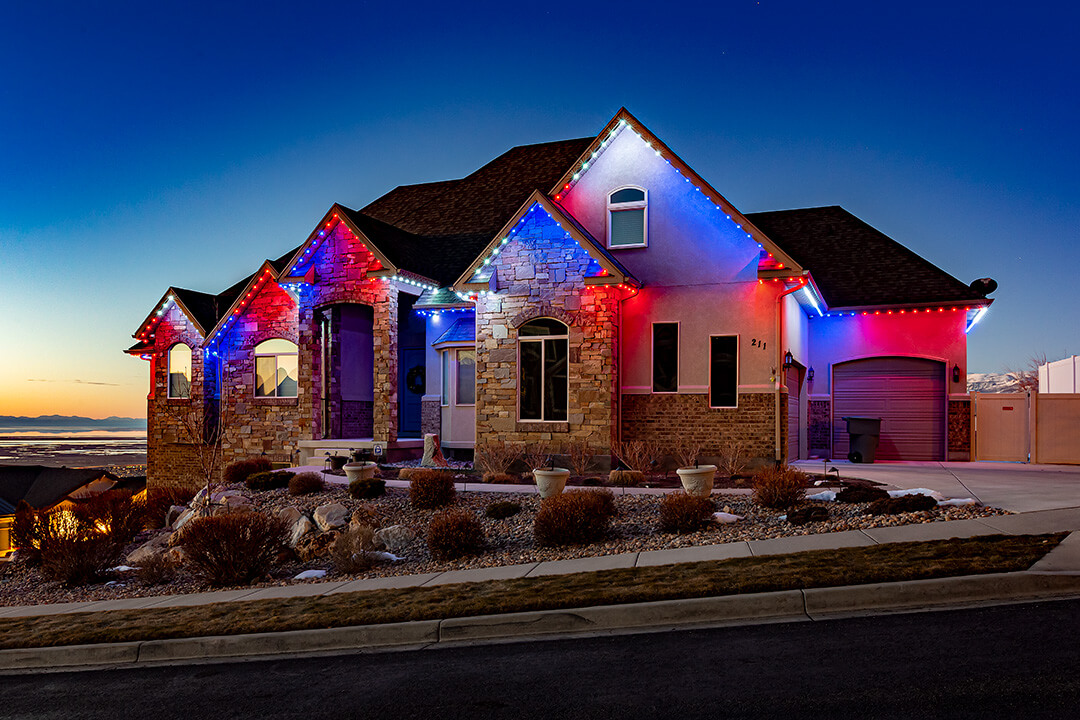 Red, white, and blue Fourth of July permanent light installation on tan home