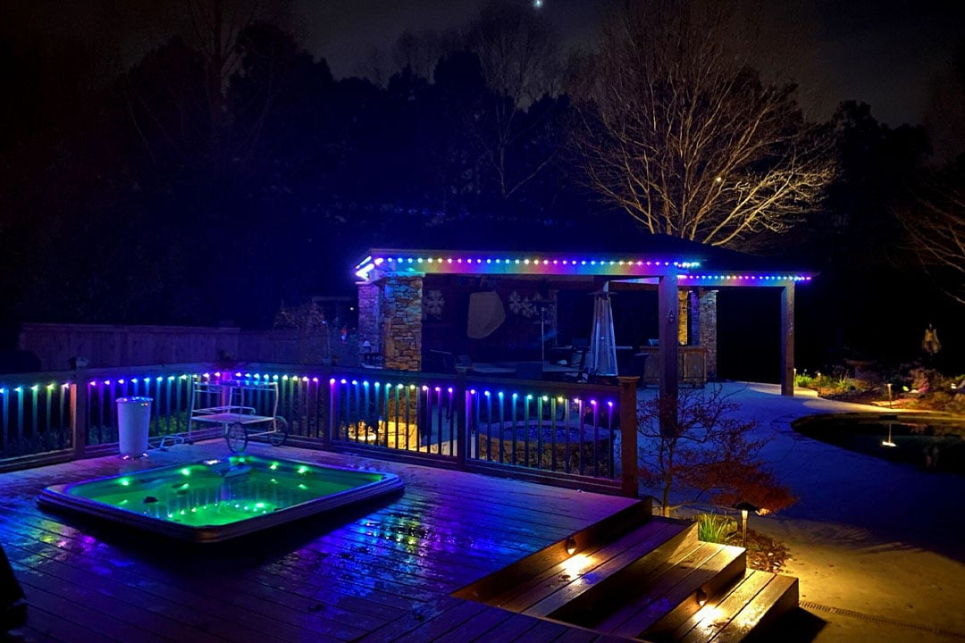 backyard patio with colorful lights on railing and pergola